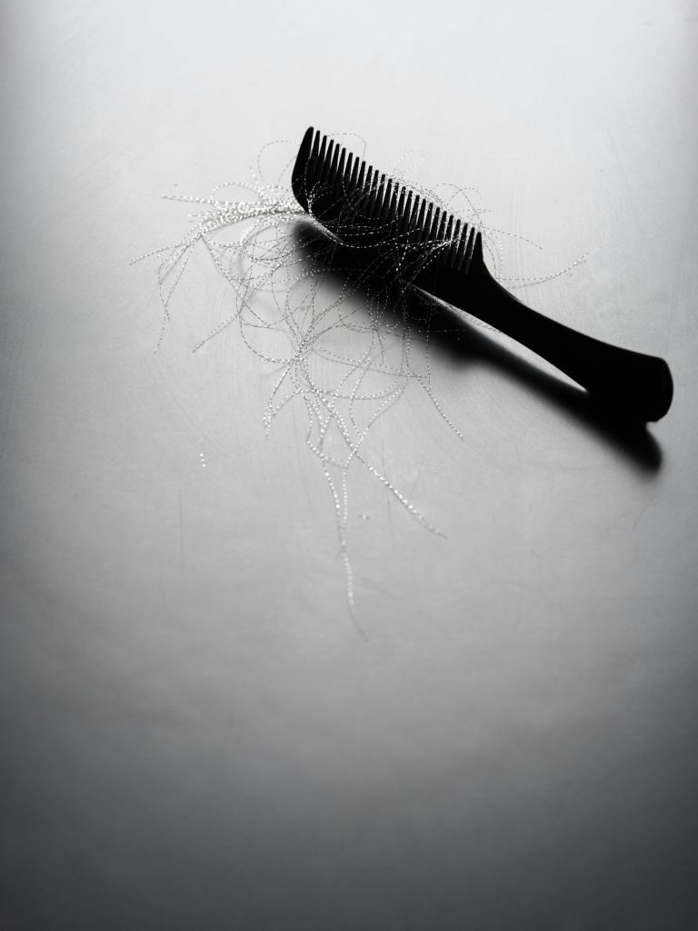 Comb with loose strands of hair on a pale surface