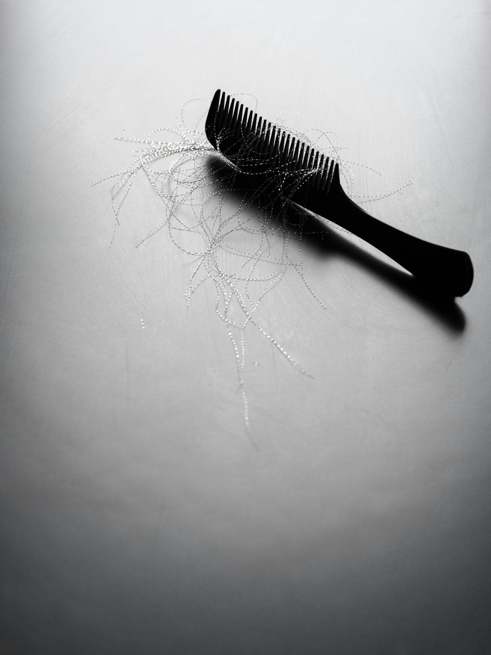 Comb with loose strands of hair on a pale surface