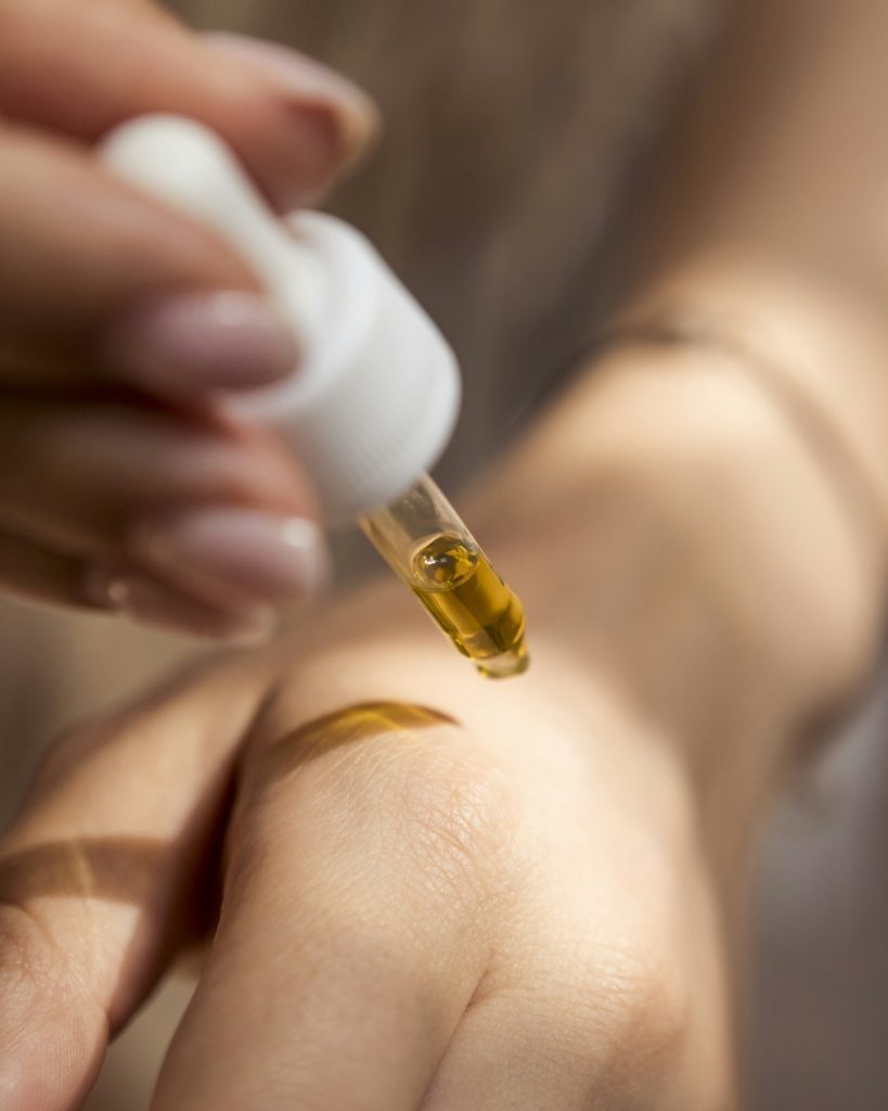 Dropper releasing a drop of oil onto skin