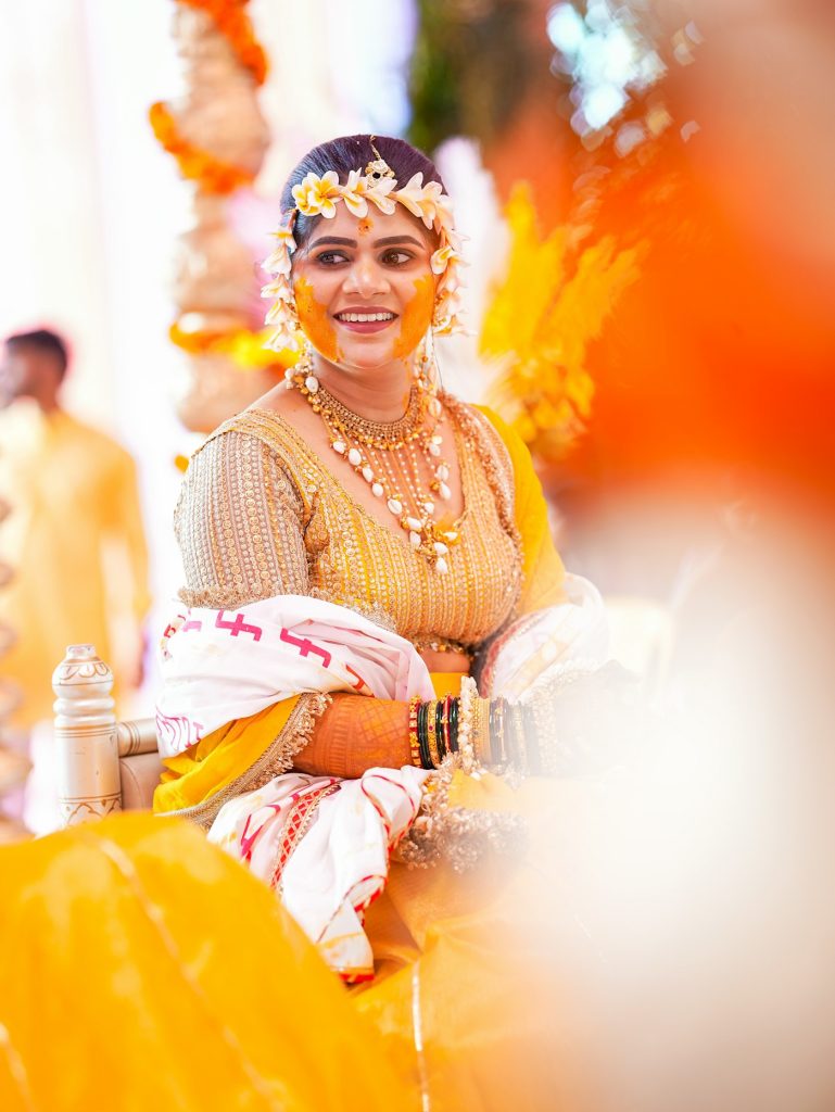 Smiling bride decorated with flowers and turmeric for a pre-wedding ceremony